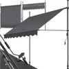 A dark gray retractable awning is shown in a studio setting against a white background. The awning is partially extended, and its frame and crank mechanism are visible. There are also two other awnings in the background, one fully retracted and one partial Náhled obrázku produktu
