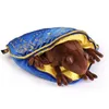 A brown plush frog is nestled inside a blue and yellow pouch with gold embroidery. Podgląd zdjęcia produktu