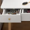 A close-up view of an open drawer of a white vanity table, filled with makeup and accessories, with a wooden floor visible below. Produktbild-Vorschau