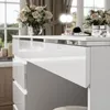 A close-up of a white dressing table with drawers, a vase of flowers, and makeup brushes. Produktbild-Vorschau