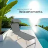 A grey sun lounger with a canopy is placed on a patio next to an infinity pool overlooking the ocean. Náhled obrázku produktu