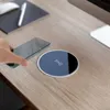 A hand is holding a smartphone over a wireless charging pad on a wooden desk. Produktbild-Vorschau
