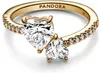 A close-up studio shot of a gold Pandora ring with two heart-shaped clear stones and small clear stones along the band. Produktbild-Vorschau