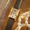 A close-up of a gold Citizen watch with a black leather strap, placed on a textured golden surface next to a strand of pearls. Podgląd zdjęcia produktu