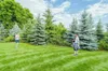 Two people are standing in a grassy backyard with trees in the background. Náhled obrázku produktu