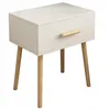 A white nightstand with a wooden drawer pull and legs, shown against a white background. Náhľad obrázku produktu