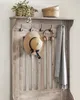 A close-up of a wooden coat rack with a hat, headphones, and a scarf hanging on it. Náhled obrázku produktu