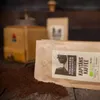A bag of coffee beans and a coffee grinder are on a wooden surface. Produktbild-Vorschau