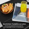 A close-up view of a black slatted table with a bowl of pastries and breadsticks, and a glass of orange juice on top of magazines. Produktbild-Vorschau