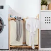 A laundry room scene with a washing machine, a bamboo laundry sorter with two beige laundry bags, and clothes. Voir les images du produit