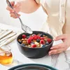 A person is adding berries to a bowl of granola with a spoon. Náhled obrázku produktu