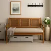 A wooden bench with a beige cushion and storage drawers underneath, placed in a hallway with a framed picture and a vase of flowers. Produktbild-Vorschau
