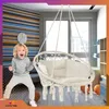 A child is excitedly posing next to a hanging chair in a room with striped wallpaper. Voir les images du produit