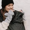 A woman wearing a black beanie and grey fingerless gloves is holding a black cover. Náhled obrázku produktu