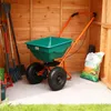 A garden spreader and tools are stored inside a wooden shed. Produktbild-Vorschau