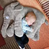 A baby sleeping on a large plush elephant pillow. Produktbild-Vorschau
