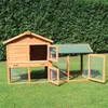 A wooden rabbit hutch with an attached run, set up on a grassy lawn with a green hedge in the background. Produktbild-Vorschau