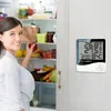 A woman is standing in front of an open refrigerator, holding an apple. A digital thermometer/hygrometer is attached to the refrigerator door. Anteprima dell’immagine prodotto