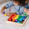A child is playing with colorful wooden beads, stringing them onto a cord. Podgląd zdjęcia produktu