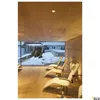A modern interior with wooden walls and ceiling, featuring several lounge chairs facing a large window with a snowy outdoor view. Produktbild-Vorschau
