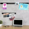 A desk with a laptop, glasses, and a plant, with two magnetic strips on a concrete wall displaying photos and artwork. Voir les images du produit