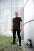 A man stands between two large industrial silos. Produktbild-Vorschau