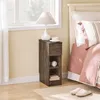 A bedside table with a lamp and a cup next to a bed. Anteprima dell’immagine prodotto