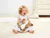 A young child is sitting on the floor, playing with a plush bunny toy. Náhled obrázku produktu