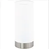 A white cylindrical table lamp with a silver base, shown against a white background. Náhľad obrázku produktu