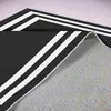 A close-up view of a black rug with white stripes, showing the corner and the underside. Produktbild-Vorschau