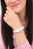 A woman wearing a pink shirt and a white and gold watch. Voir les images du produit