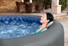 A woman relaxing in an inflatable hot tub outdoors. Produktbild-Vorschau
