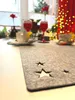 A table setting with a grey felt table runner with cut-out stars, two glasses of red liquid, and two cups and saucers. Produktbild-Vorschau