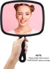 A hand holding a black hand mirror with a young woman's reflection in it. Produktbild-Vorschau