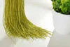 A close-up of green thread curtains hanging down, with a white potted plant in the background. Produktbild-Vorschau