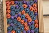 A close-up view of a wooden tray filled with colorful wooden pegs. Produktbild-Vorschau