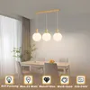 A dining room with a table and chairs, featuring a pendant light fixture above the table. Voir les images du produit