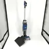 A Shark Hydrovac wet and dry vacuum cleaner is shown standing upright on a white background, with its cleaning head and a black mat in the foreground. Podgląd zdjęcia produktu
