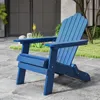 A blue Adirondack chair sits on a paved patio in a garden setting. Produktbild-Vorschau