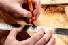 Hands using a pencil and ruler to mark a piece of wood. Podgląd zdjęcia produktu