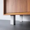 A close-up view of the bottom of a wooden cabinet, showing its modern, square, silver and white legs. Produktbild-Vorschau