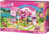 The image shows the packaging of a toy building set, featuring a pink dollhouse and figures. Náhled obrázku produktu