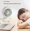 A white desk fan is placed on a wooden desk next to a laptop, with a woman sleeping peacefully in the background. Anteprima dell’immagine prodotto