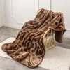 A brown blanket with a geometric pattern is draped over a chair, resting on a white rug. Podgląd zdjęcia produktu