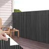 A balcony with a wooden deck, a chair, a table with tea set, and a dark gray privacy screen. Produktbild-Vorschau