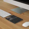 A close-up view of a computer setup on a wooden desk, featuring a keyboard, a numeric keypad, a trackpad, and a mouse. Produktbild-Vorschau