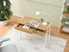 A desk with a lamp, plant, and open book in a room setting. Voir les images du produit