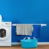 A laundry room scene with a washing machine, a drying rack with clothes, and a laundry basket. Produktbild-Vorschau