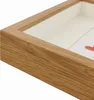 A close-up, angled view of a wooden shadow box frame with a white insert and a hint of a colorful artwork inside. Náhľad obrázku produktu