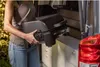 A person is placing a portable grill into the back of a van. Náhľad obrázku produktu